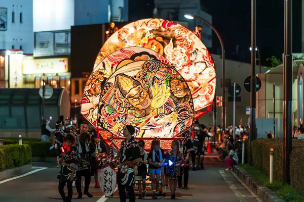 Hirosaki, Aomori, Japonya - 5 Ağustos 2024: Hirosaki Neputa Festivali. Uçsuz bucaksız ve aydınlık hayran şekilli Neputa şamandırası bir müzik grubuyla birlikte sokaklarda süzülüyor..