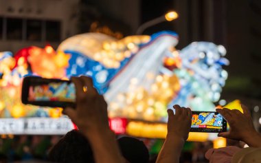 Aomori Şehri, Japonya - 6 Ağustos 2024: Bir izleyici Aomori Nebuta Festivali geçit töreninde muhteşem, aydınlık bir şamandırayı fotoğraflamak için akıllı telefon kullanıyor.