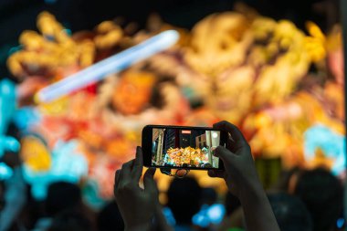 Aomori Şehri, Japonya - 6 Ağustos 2024: Bir izleyici Aomori Nebuta Festivali geçit töreninde muhteşem, aydınlık bir şamandırayı fotoğraflamak için akıllı telefon kullanıyor.