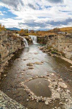 Sonbaharda Crowsnest Nehri 'ndeki Lundbreck Şelalesi' nin arkasında demiryolu köprüsü var. Alberta, Kanada.