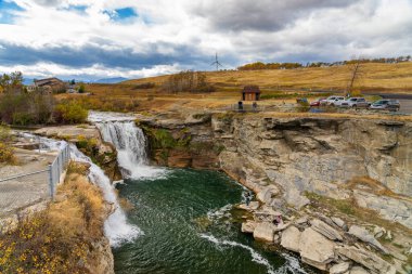 Alberta, Canada - Oct 9 2020 : Lundbreck Falls on the Crowsnest River in autumn, with a railway bridge in the background. 