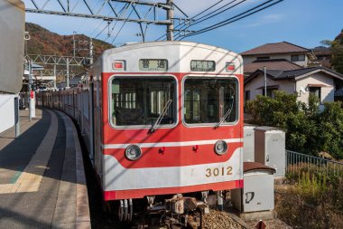 Hyogo, Japonya - 11 Aralık 2024: Kobe Elektrik Demiryolu hattında Arima Onsen 'e giden yerel bir tren, arka planda sonbahar yeşillikleri var.