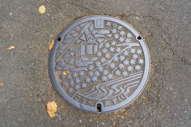 Hyogo, Japonya - 11 Aralık 2024: Arima Onsen, Kobe 'de sonbahar akçaağaç yaprakları ve bir halat içeren eşsiz bir tasarımı olan rögar kapağı.