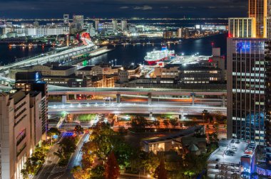 Hyogo, Japonya - 11 Aralık 2024: Kobe Şehri panoramik gece manzarası, aydınlatılmış binalar, köprüler ve liman bölgesi.
