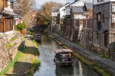 Omihachiman, Shiga, Japonya - 16 Aralık 2024: Geleneksel bir wasen teknesi, güzel bir sonbahar günü, ünlü bir sinema kanalı olan Hachiman-bori kanalında dolaşır..