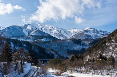 Shirakawa-go 'nun batı kıyısından Hakusan Dağı' nın (Hakusan) karla kaplı görkemli dağlarına bakan manzaralı bir kış manzarası. Gifu, Japonya.