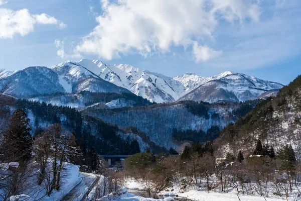 Shirakawa-go 'nun batı kıyısından Hakusan Dağı' nın (Hakusan) karla kaplı görkemli dağlarına bakan manzaralı bir kış manzarası. Gifu, Japonya.