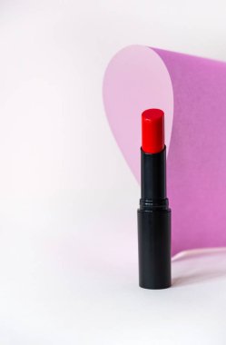 Beyaz ve pembe arka planda güzel kırmızı ruj. Profesyonel makyaj ürünü. Ruj, pastel arka planda hayat dolu..