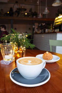 Yeni servis edilmiş bir fincan kapuçino ve bir kafedeki ahşap masada Japon shu kreması..