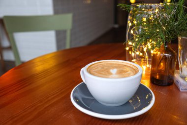 Bir kafede, ahşap bir masanın üzerinde kahve ile taze servis edilmiş kapuçino..