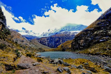 Peru 'nun yüksek And Dağları' nın Cordeleira Blanca bölgesinde uzak kar manzaralı sakin bir göl..