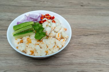 Buharda pişmiş yengeç etli sarımsaklı pilav, soğan, salatalık ve ahşap masada kırmızı biber.