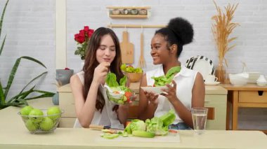 Siyah ve beyaz genç arkadaşlar mutfakta sebze salatası yapmak için birlikte çalışıyorlar. Sağlıklı yemek..