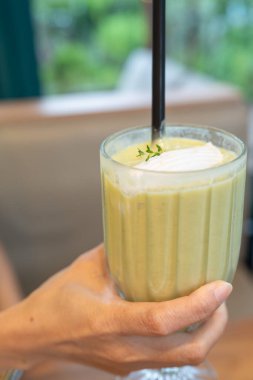 Yakın plan, elinde bir bardak yeşil çay ve hindistan cevizi suyu tutan bir kadın eli.