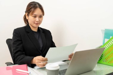 Dizüstü bilgisayarda çalışan Asyalı iş kadını, ofiste mali belge raporlarını okuyor. Muhasebeci, girişimci, menajer. İş kadını dizüstü bilgisayar ve dijital tablet kullanarak belge hazırlıyor.