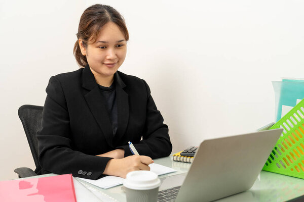 Азиатская бизнесвумен работает на ноутбуке, читает финансовый отчет в офисе. Бухгалтер, предприниматель, менеджер. Деловая женщина делает документ с помощью ноутбука компьютера и цифрового планшета.