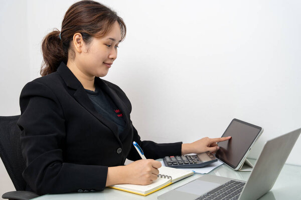 Азиатская бизнесвумен, работающая над ноутбуком и цифровым планшетом, читает финансовый отчет в офисе. Бухгалтер, предприниматель, менеджер. Деловая женщина делает документы с помощью ноутбука.