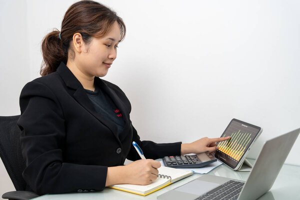 Азиатская бизнесвумен, работающая над ноутбуком и цифровым планшетом, читает финансовый отчет в офисе. Бухгалтер, предприниматель, менеджер. Деловая женщина делает документы с помощью ноутбука.