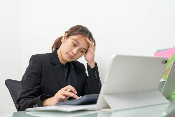 Азиатская деловая женщина, работающая над цифровым талбетом, читающая финансовый отчет, чувствующая себя серьезной или напряженной из-за низких показателей доходов. Бухгалтер, предприниматель, менеджер.