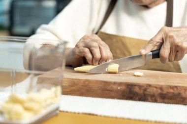 Yakın plan, yaşlılar evde mutfakta yemek pişiriyor, sebze ve bebek mısırı kesiyorlar..