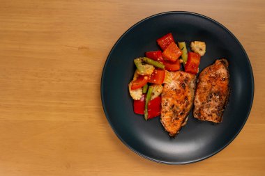 Grilled or Fried salmon steaks with fresh vegetables on plate. Top view on wooden table.