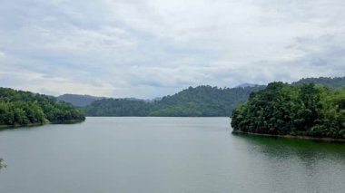 Kuala Kuala Kubu Bharu, Selangor, Malezya 'daki güzel göl ve yeşil dağ doğal manzarası. Ada ağaçları ve bulutlarıyla büyük bir nehir kıyısı.