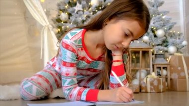 Bir çocuk ağacın altına Noel Baba 'ya mektup yazıyor. Seçici odaklanma. Çocuk.