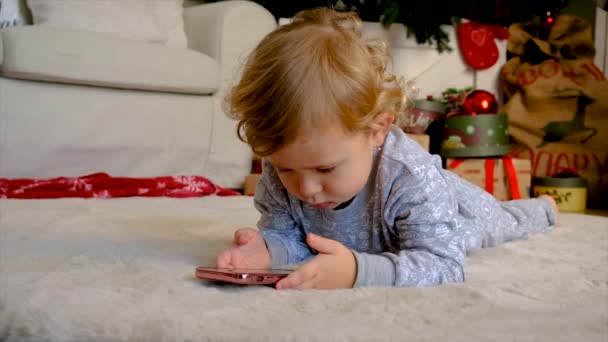 Bir Çocuk Noel Ağacının Yanında Bir Telefonla Oynuyor Seçici Odaklanma — Stok video