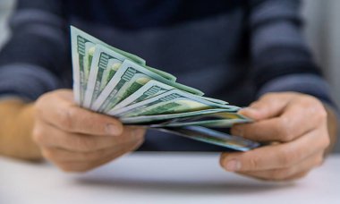 Bir adam dolar olarak para sayar. Seçici odaklanma. İnsanlar.