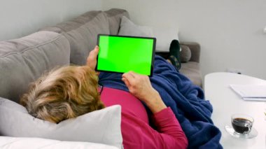 Yaşlı kadın tablet yeşili arka plana bak. Seçici odaklanma. yeşil