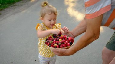 Bir çocuk ve büyükanne bahçede böğürtlen yerler. Seçici odaklanma. Çocuk.