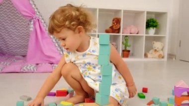 The child plays in the childrens room with a wooden constructor. Selective focus. Kid.
