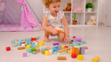 The child plays in the childrens room with a wooden constructor. Selective focus. Kid.