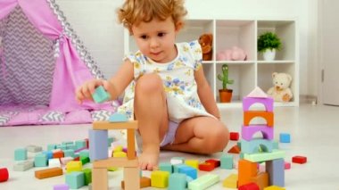 The child plays in the childrens room with a wooden constructor. Selective focus. Kid.