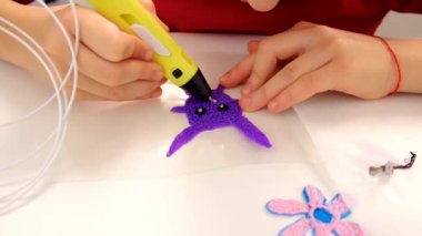 The child draws with a 3D pen. Selective focus. Kid.