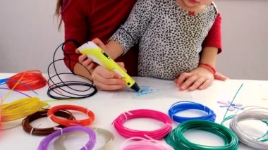 The child draws with a 3D pen. Selective focus. Kid.