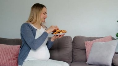Hamile bir kadın tatlı bir çörek yer. Seçici odaklanma. Yiyecek..