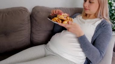 Hamile bir kadın tatlı bir çörek yer. Seçici odaklanma. Yiyecek..