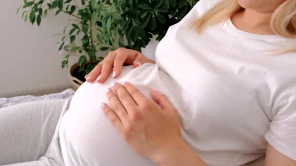 妊娠中の女性がベッドに横になって腹を撫でている 選択的フォーカス — ストック動画