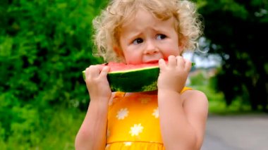 The child eats watermelon in summer. Selective focus. Kid.