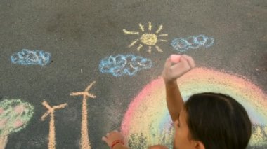 Bir çocuk kaldırıma bir gökkuşağı çizer. Seçici odaklanma. Çocuk.