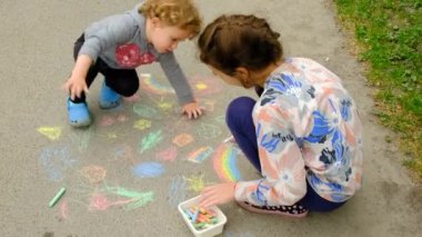 Bir çocuk asfalta tebeşirle resim çizer. Seçici odaklanma. çocuk.