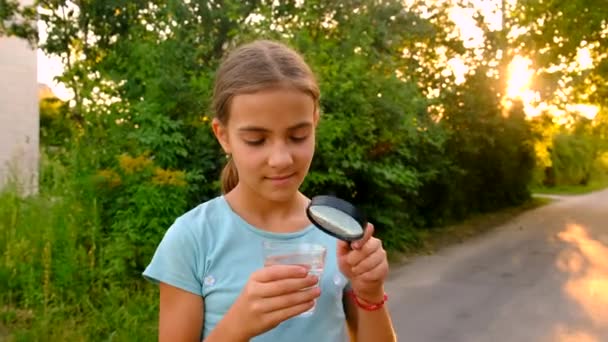 Een Kind Kijkt Naar Een Glas Water Met Een Vergrootglas — Stockvideo