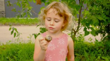 Bir çocuk bahçede bir salyangozla oynuyor. Seçici odaklanma. Doğa.