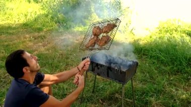 Bir adam dışarıda ateşte et pişiriyor. Seçmeli odaklanma. Doğa.
