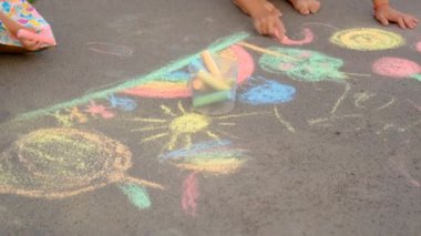 Çocuklar asfalta tebeşirle çizer. Seçici odaklanma. Çocuk.