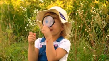 Büyüteci olan çocuk bitkiye bakıyor. Seçici odaklanma. Doğa.