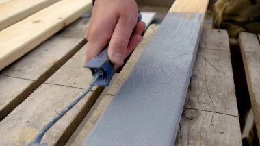 Bir adam bir tahtayı boyayla boyuyor. Seçici odaklanma. İnsanlar.