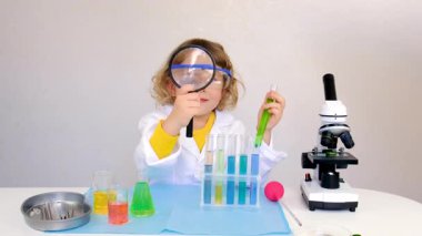 Test tüpleri, reaktörleri ve mikroskobu olan bir çocuğun laboratuvar incelemesi. Seçici odaklanma. çocuk.