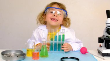Test tüpleri, reaktörleri ve mikroskobu olan bir çocuğun laboratuvar incelemesi. Seçici odaklanma. çocuk.